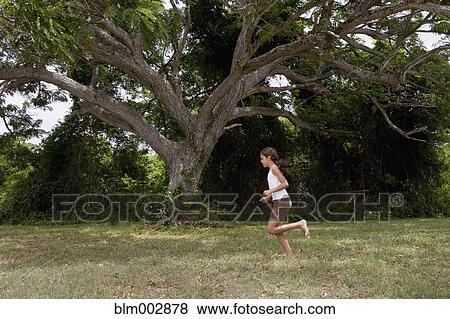 Stock Photo - Hispanic girl running barefoot through grass. Fotosearch