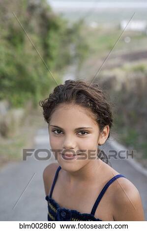 Stock Image - Hispanic girl standing in remote roadway. Fotosearch