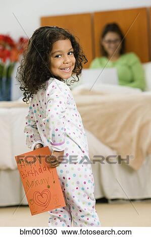 Stock Image - Hispanic girl with birthday card for mother. Fotosearch