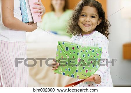 Stock Image - Hispanic girl with birthday gift for mother. Fotosearch