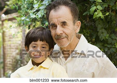 Stock Image - Hispanic grandfather and grandson on patio. Fotosearch