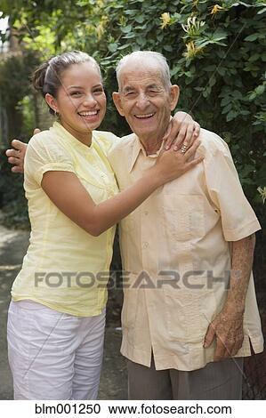 Stock Image - Hispanic grandfather hugging granddaughter. Fotosearch