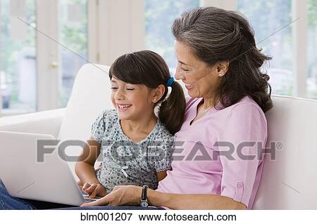 Stock Photo - Hispanic grandmother and granddaughter using laptop. Fotosearch