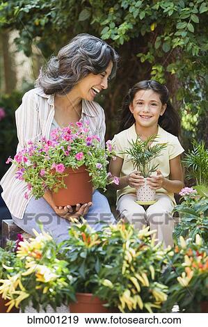 Hispanic grandmother and granddaughter holding plants in garden View Large Photo Image Stock Photo - Hispanic grandmother and granddaughter holding plants in garden. Fotosearch