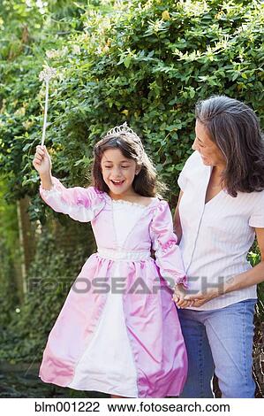 Stock Image - Hispanic grandmother with granddaughter wearing princess costume. Fotosearch