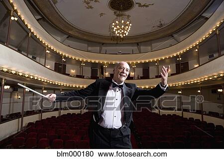 Stock Image - Hispanic male conductor in empty theater. Fotosearch
