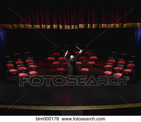 Stock Photo - Hispanic male conductor in front of empty chairs. Fotosearch