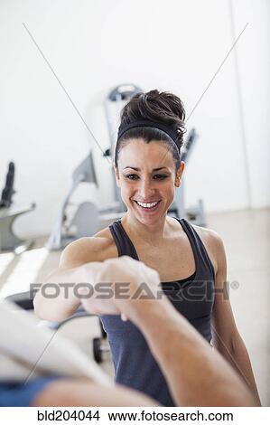 Picture - Hispanic man cheering with trainer in gym. Fotosearch