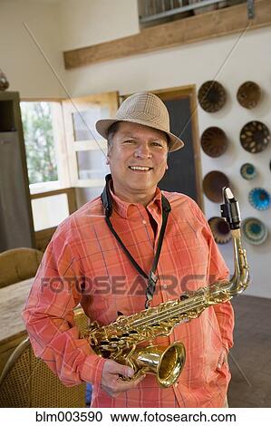 Stock Image - Hispanic man holding saxophone. Fotosearch