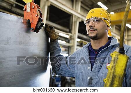 Stock Image - Hispanic man in warehouse with sheet metal. Fotosearch