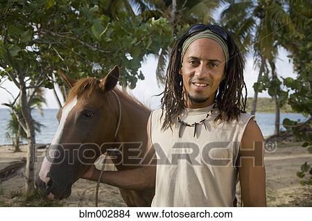 Picture - Hispanic man leading horse near beach. Fotosearch