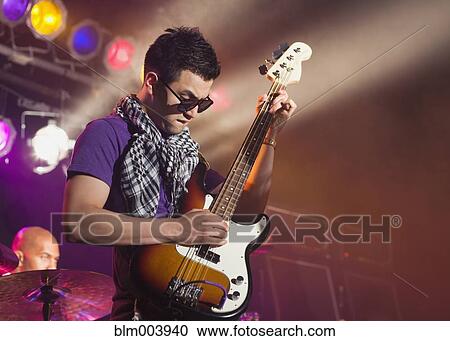 Stock Image - Hispanic man playing electric guitar onstage. Fotosearch