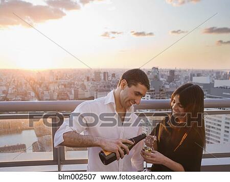 Stock Photo - Hispanic man pouring champagne for girlfriend. Fotosearch