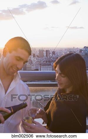 Stock Photograph - Hispanic man pouring champagne for girlfriend. Fotosearch