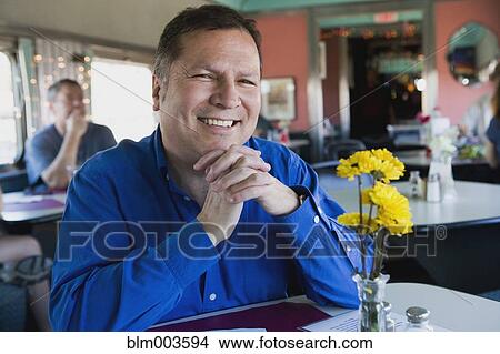 Picture - Hispanic man sitting at diner table. Fotosearch