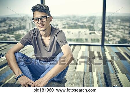 Stock Image - Hispanic man sitting on floor. Fotosearch