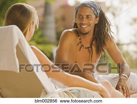 Hispanic man sitting on lounge chair talking to girlfriend View Large Photo Image Stock Photograph - Hispanic man sitting on lounge chair talking to girlfriend. Fotosearch
