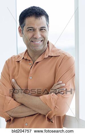 Stock Photo - Hispanic man smiling in window. Fotosearch