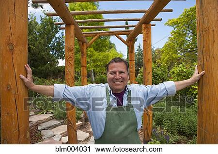 Stock Image - Hispanic man with arms outstretched between wooden beams. Fotosearch