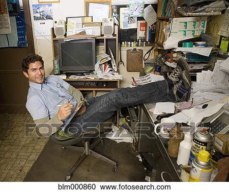 Stock Image - Hispanic mechanic in garage office. Fotosearch
