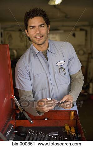 Stock Image - Hispanic mechanic sorting tools. Fotosearch