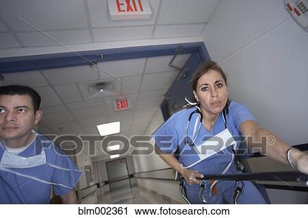 Stock Image - Hispanic medical professionals pushing gurney. Fotosearch