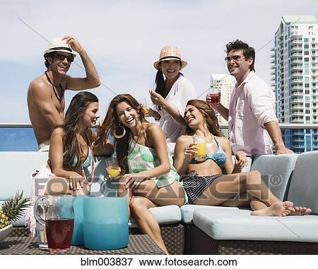 Stock Photo - Hispanic men and women partying on rooftop. Fotosearch