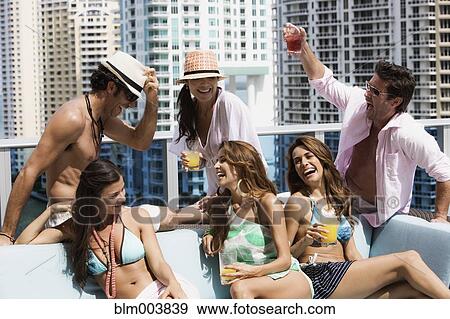 Stock Photo - Hispanic men and women partying on rooftop. Fotosearch
