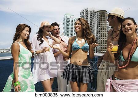 Stock Photography - Hispanic men and women partying on rooftop. Fotosearch