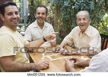 Stock Photography - Hispanic men playing dominos on patio. Fotosearch