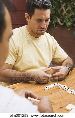 Stock Image - Hispanic men playing dominos. Fotosearch