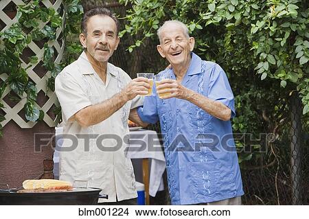 Picture - Hispanic men toasting on patio. Fotosearch