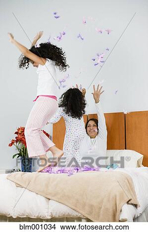 Hispanic mother and daughters throwing feathers in bedroom View Large Photo Image Picture - Hispanic mother and daughters throwing feathers in bedroom. Fotosearch