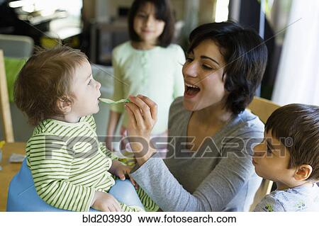 Hispanic mother feeding toddler in kitchen View Large Photo Image Stock Image - Hispanic mother feeding toddler in kitchen. Fotosearch