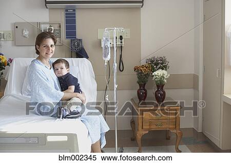 Stock Photography - Hispanic mother in hospital bed hugging son. Fotosearch