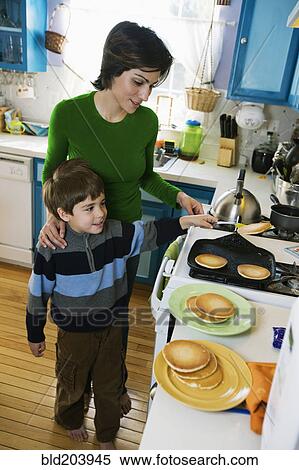 Stock Photography - Hispanic mother making breakfast for son. Fotosearch