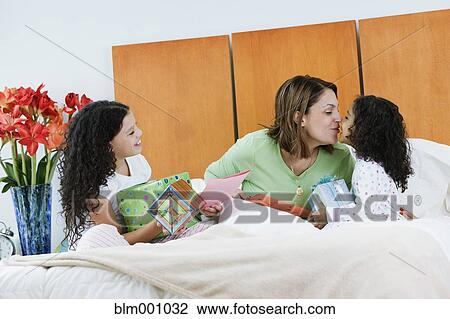 Stock Image - Hispanic sisters giving mother birthday gifts. Fotosearch