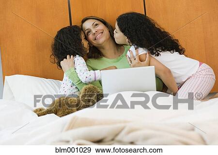 Hispanic sisters kissing mother on bed in bedroom View Large Photo Image Stock Photo - Hispanic sisters kissing mother on bed in bedroom. Fotosearch