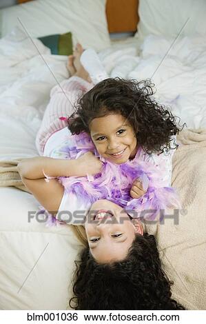 Hispanic sisters laying on bed View Large Photo Image Stock Photograph - Hispanic sisters laying on bed. Fotosearch