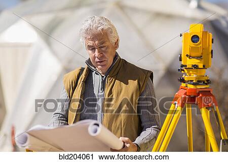Stock Image - Hispanic surveyor working outdoors. Fotosearch