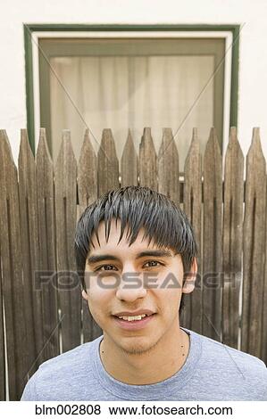 Stock Photo - Hispanic teenage boy posing in front of fence. Fotosearch