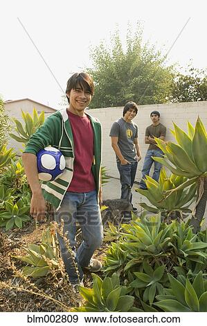 Stock Photo - Hispanic teenage boys and man with soccer ball. Fotosearch