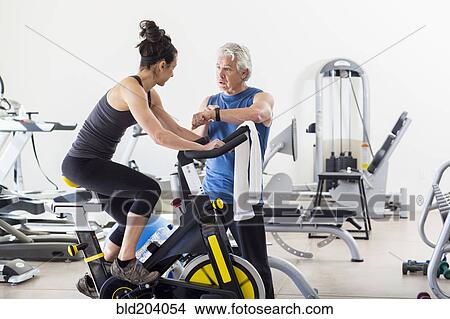 Picture - Hispanic trainer working with woman in gym. Fotosearch