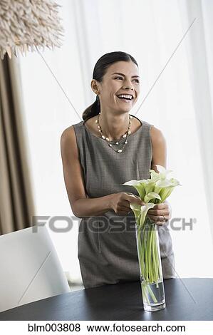 Stock Photo - Hispanic woman arranging calla lilies in vase. Fotosearch