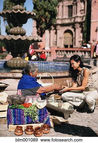 Stock Photo - Hispanic woman buying tortilla from street vendor. Fotosearch