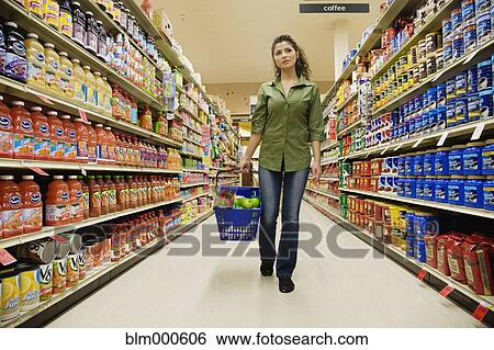 Stock Photograph - Hispanic woman carrying basket in grocery store. Fotosearch