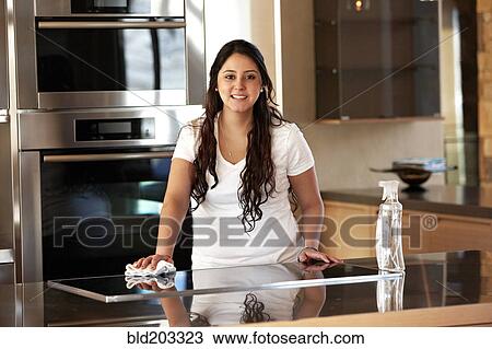 Stock Image - Hispanic woman cleaning kitchen. Fotosearch