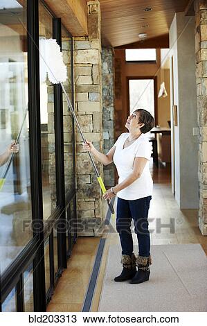 Stock Image - Hispanic woman dusting windows. Fotosearch