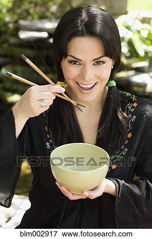 Hispanic woman eating from bowl with chopsticks View Large Photo Image Stock Photo - Hispanic woman eating from bowl with chopsticks. Fotosearch