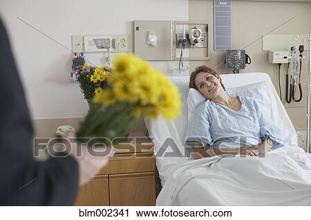 Stock Image - Hispanic woman getting flowers in hospital. Fotosearch